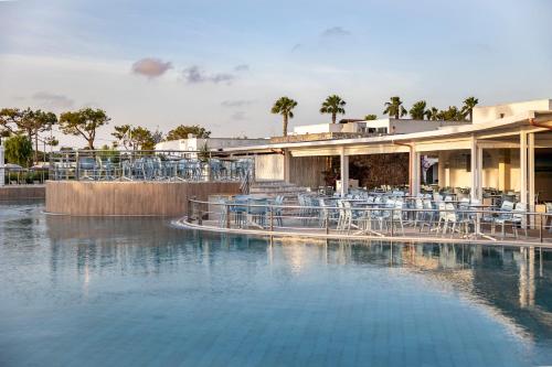 a resort with a pool of water with tables and chairs at Blu Salento Village in Sant'Isidoro