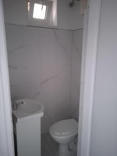 a white bathroom with a toilet and a window at R4 Rolléder Apartman-ház in Siklós