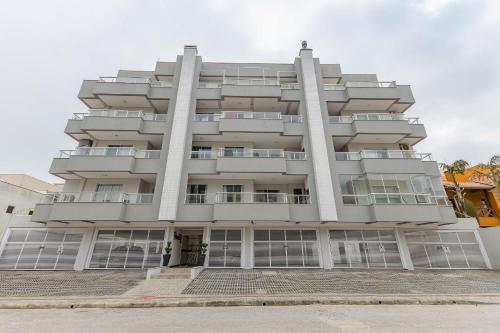a tall white building with columns at Excelente Apartamento a 2 minutos da Praia de Bombas in Bombas