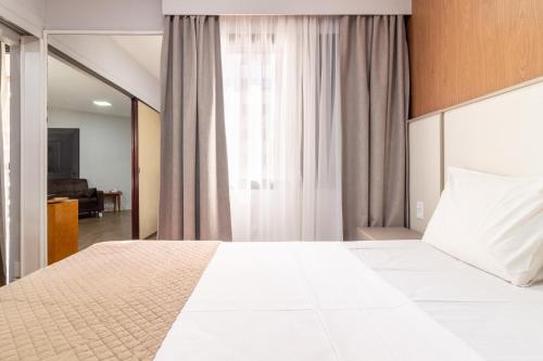 a bedroom with a large white bed and a window at H4 Fortune Jardins in Sao Paulo