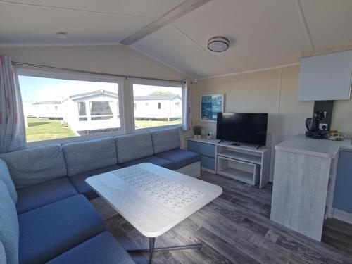 a living room with a blue couch and a table at Golden Sands sea holiday beach activities and relax in Mablethorpe