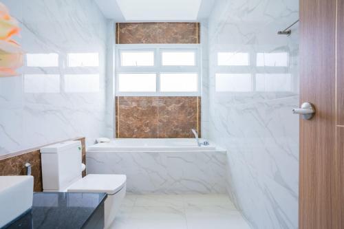 a bathroom with a tub and a toilet and a sink at Beverly Hills Pool Villa Na Jomtien in Na Jomtien