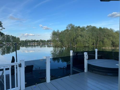 a deck with a table and chairs on a body of water at Lakeside Dorchester Lodge - Hot Tub with Fishing Peg in Tattershall
