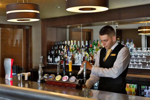 a man standing at a bar preparing a drink at Best Western Heath Court Hotel in Newmarket