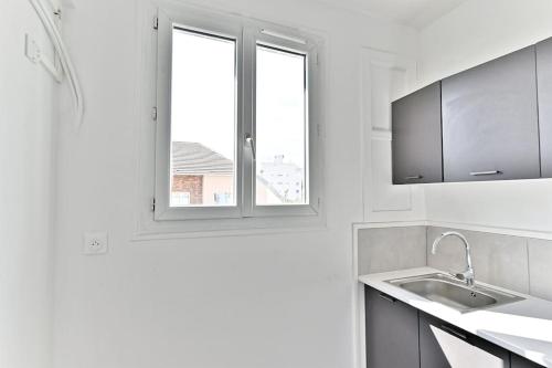 une cuisine blanche avec un évier et une fenêtre dans l'établissement Magnifique studio neuf au centre de Montreuil, à Montreuil