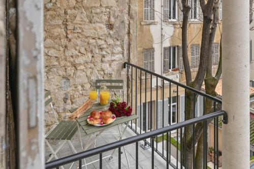 une table avec une assiette de fruits et deux verres de jus d'orange dans l'établissement AMICAL-Marseille-Coeur de ville Balcon, à Marseille