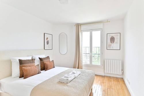 une chambre blanche avec un grand lit blanc et une fenêtre dans l'établissement Appartement spacieux 50m2 Proche de la capitale, à Montreuil