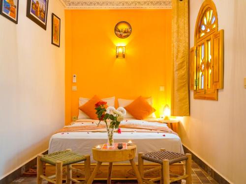 a bedroom with a bed with a vase of flowers on a table at Riad Dar Yassine in Marrakech