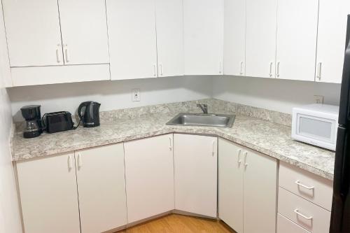 Una cocina con gabinetes blancos, un fregadero y un microondas. en Miami Beach Apartments by MiaRentals, en Miami Beach