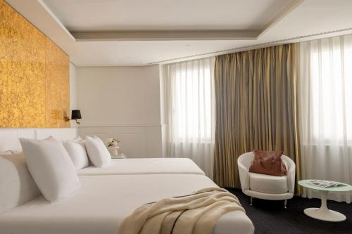 a hotel room with a bed and a chair at Hotel Colón Gran Meliá - The Leading Hotels of the World in Seville