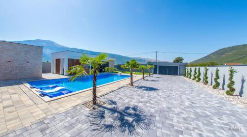 a swimming pool with palm trees and a house at Villa River in Mostar