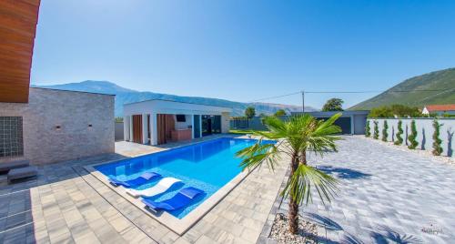 a swimming pool with a palm tree next to a house at Villa River in Mostar