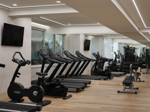 a gym with a row of treadmills and ellipticals at Atlantica Princess Hotel in Ixia