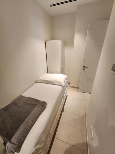a small white room with a bed and a shower at Solo RealtyHH Apartments - Address Residence Fujairah in Sharm