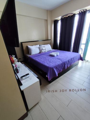 a bedroom with a bed with purple sheets and a tv at Condotel Near Naia Terminal 3 in Manila