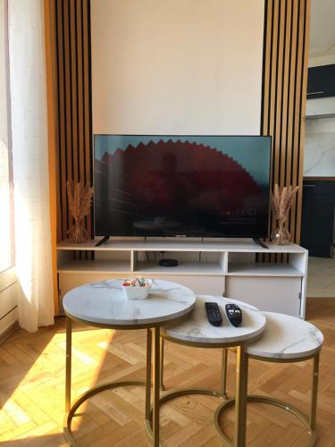 - un salon avec deux tables et une télévision dans l'établissement Votre Refuge à proximité des Plages et du Stade Vélodrome, à Marseille