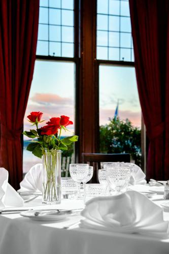 a table with a vase with red roses on it at Bunchrew House Hotel in Inverness