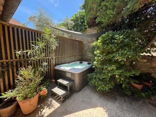 a backyard with a hot tub and some plants at La Maison des Vendangeurs - TABLE D'HÔTES le soir du jeudi au dimanche- Jacuzzi - Balnéo SPA - ACCES PISCINE pour toutes les chambres sauf STUDIO COQUET- Piscine de mai à mi-octobre in Martignargues