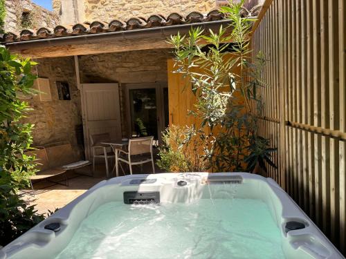 a jacuzzi tub in the yard of a house at La Maison des Vendangeurs - TABLE D'HÔTES le soir du jeudi au dimanche- Jacuzzi - Balnéo SPA - ACCES PISCINE pour toutes les chambres sauf STUDIO COQUET- Piscine de mai à mi-octobre in Martignargues