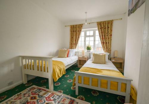 a bedroom with two beds and a window at Cosy Inn near Luton Station, Mall and Luton Airport 10 Min in Luton
