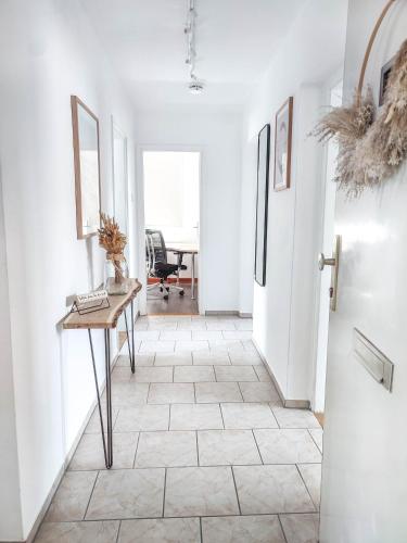 a hallway with white walls and a table with a mirror at Business & Leisure Apartment in Ingolstadt