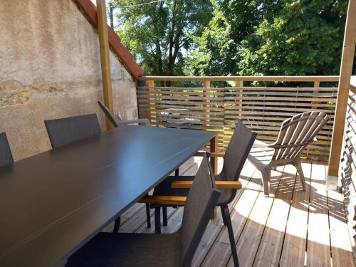 une table et des chaises noires sur une terrasse en bois dans l'établissement Appartement 4 voyageurs, à Verneuil-sur-Igneraie