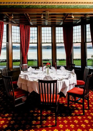 a dining room with a white table with chairs and windows at Bunchrew House Hotel in Inverness