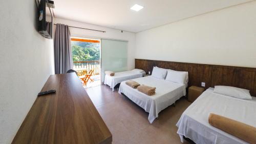 a hotel room with two beds and a desk at Pousada Canyons in Capitólio
