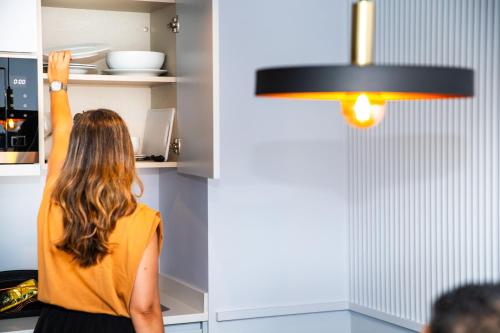 a woman standing in a kitchen looking into a refrigerator at VIP Executive Suites do Marquês Hotel in Lisbon