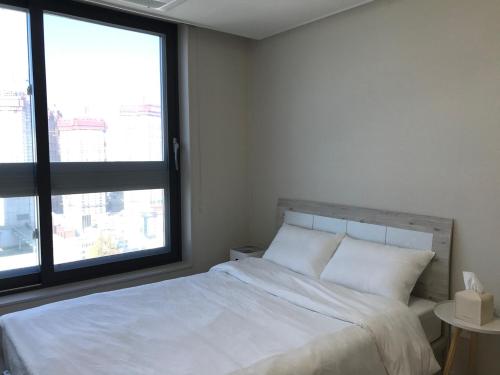 a bedroom with a white bed with a large window at Tempus urban stay hotel in Daegu