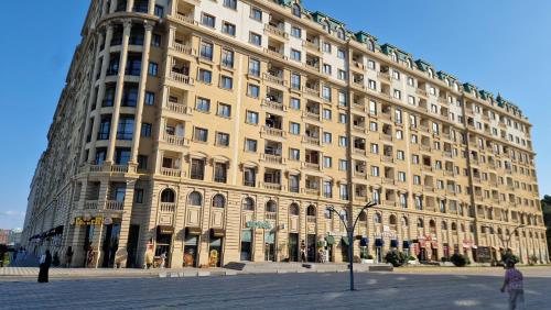 a large beige building with people standing in front of it at Sumgait Seaside Apartment in Sumqayyt