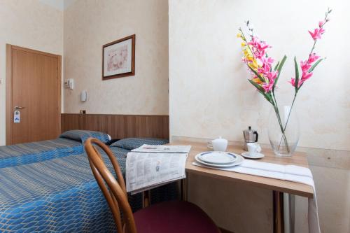 a room with a bed and a table with a vase of flowers at Residence Lepontina in Milan
