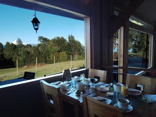 a table in a room with a large window at Lodge El Taique in Puyehue