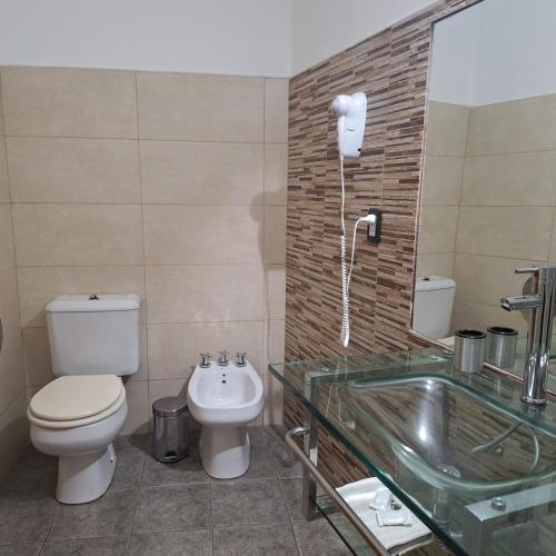 a bathroom with a toilet and a sink and a tub at Hotel Antiguo Camino in Villa General Belgrano