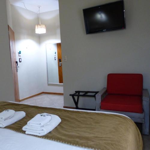 a hotel room with a bed and a red chair at Hotel Antiguo Camino in Villa General Belgrano