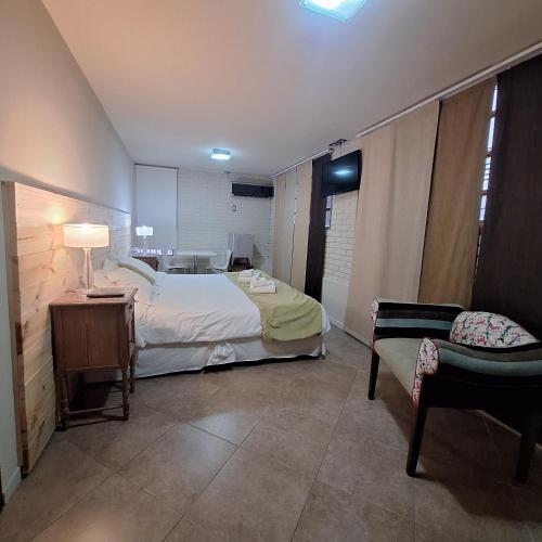 a bedroom with a bed and a chair in a room at Hotel Antiguo Camino in Villa General Belgrano