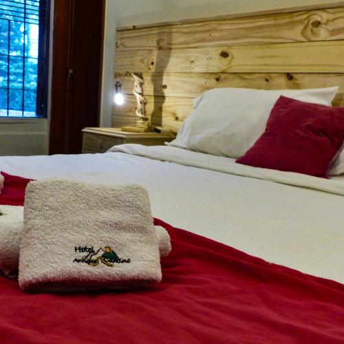 a white bed with red pillows and a blanket at Hotel Antiguo Camino in Villa General Belgrano
