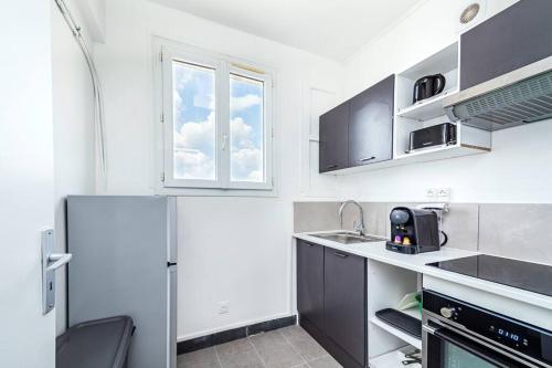 une cuisine blanche avec un réfrigérateur et une fenêtre dans l'établissement Charmant studio en banlieue parisienne - Montreuil, à Montreuil