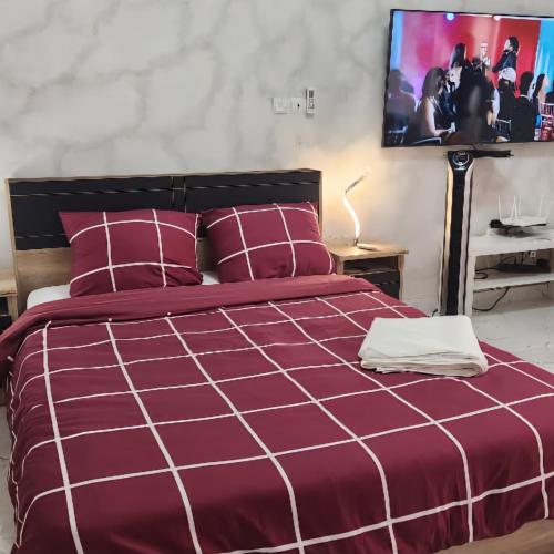 a bedroom with a purple bed with a tv on the wall at Over cloud 1 in Marcory