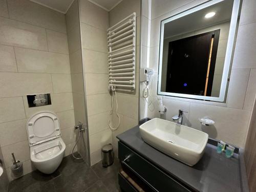 a bathroom with a sink and a toilet and a mirror at Business class studio with the Mountain View 115А in Batumi