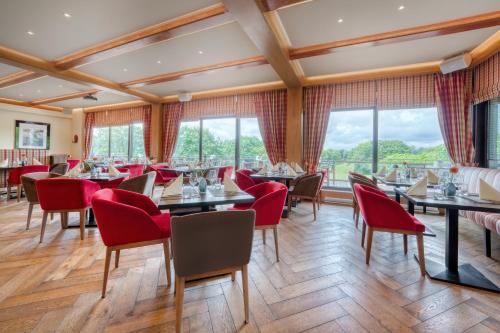 a dining room with tables and chairs and windows at Strandgrün Golf- & Spa Resort in Timmendorfer Strand