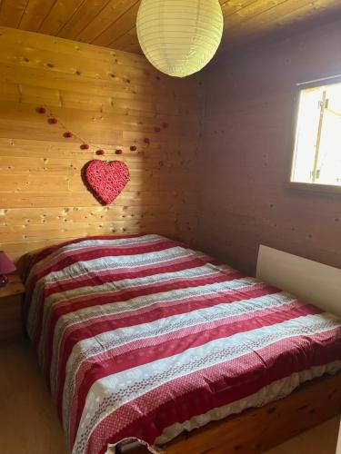 une chambre avec un lit avec un cœur sur le mur dans l'établissement Chalet dans le Haut-Jura, à Saint-Laurent-en-Grandvaux