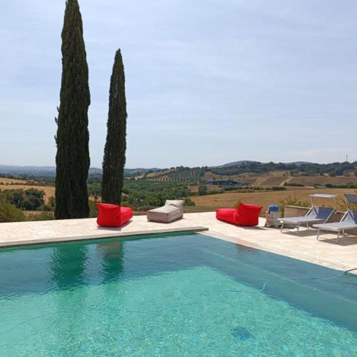 a swimming pool with chairs and a table and trees at Villa Pieve Vecchia in Campagnatico