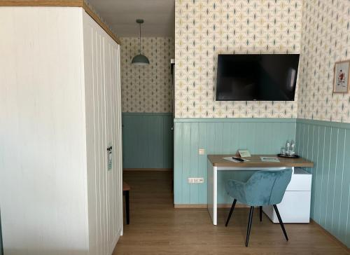a room with a table and a television on a wall at SCHULZENS Brauerei & Hotel in Tangermünde