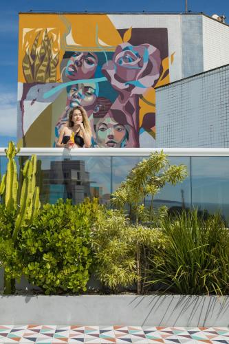 a woman standing in front of a mural on a building at Royal Urban Macaé Hotel in Macaé