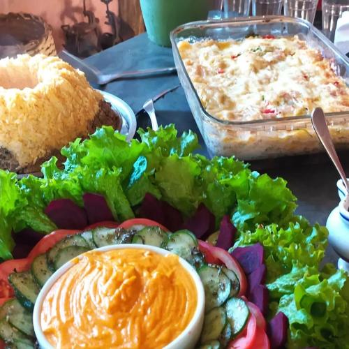 a plate of food with vegetables and a dish of dip at Sitio Alecrim Gastronomia e Hospedaria in Alagoa