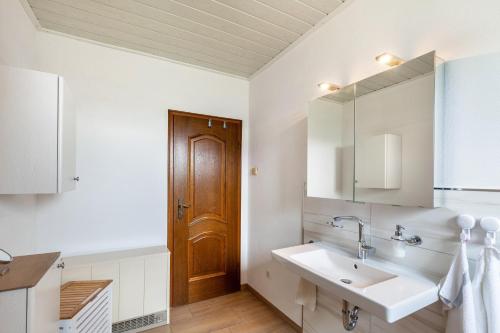 a bathroom with a sink and a wooden door at Rosi's Ferienwohnung in Daun