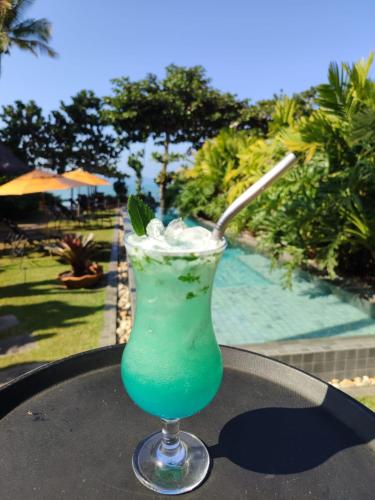 a green drink sitting on a table next to a pool at Pousada TeMoana in Ubatuba