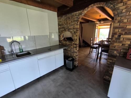 une cuisine avec des placards blancs et un mur en briques dans l'établissement Gite Belle Vue Xertigny, à Xertigny
