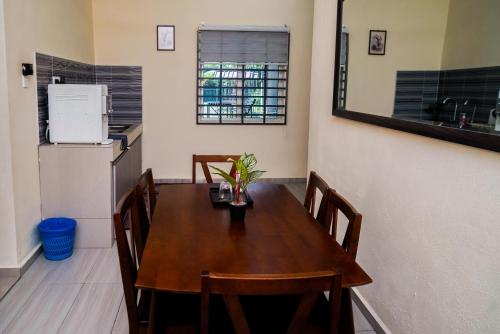 a dining room with a wooden table and a kitchen at Adorable 2-bedroom home with Pool, Wi-Fi and BBQ in Rembau